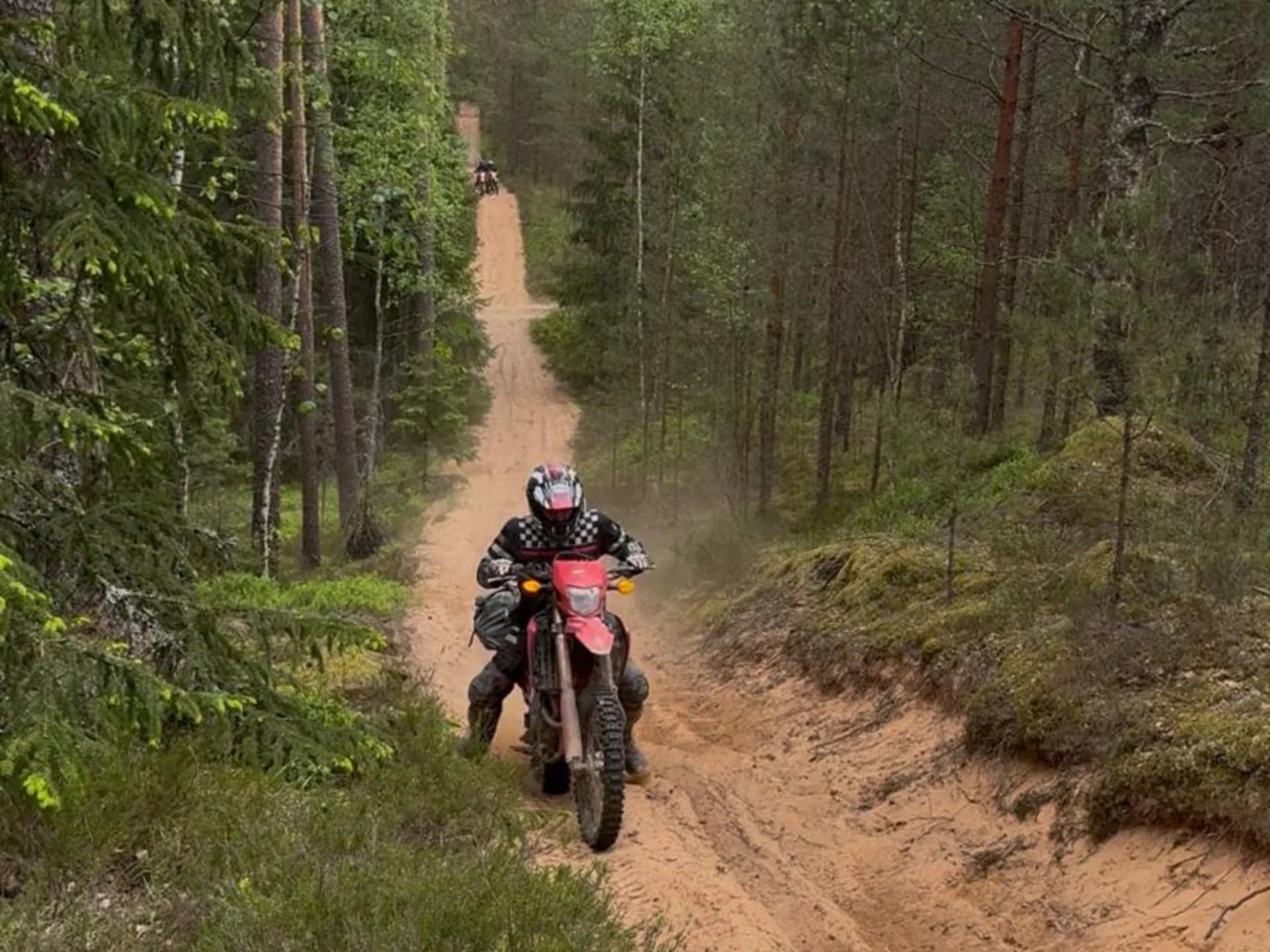 Enduro rider crossing a shallow river with water splashes and forest background
